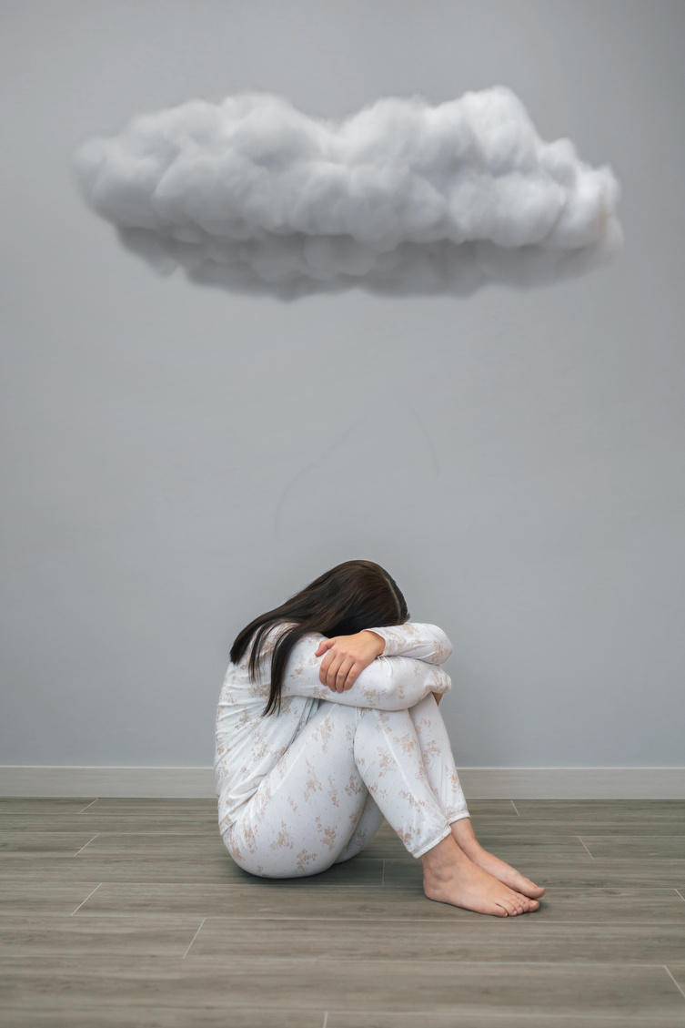 Woman with mental disorder and suicidal thoughts crying under a dark cloud